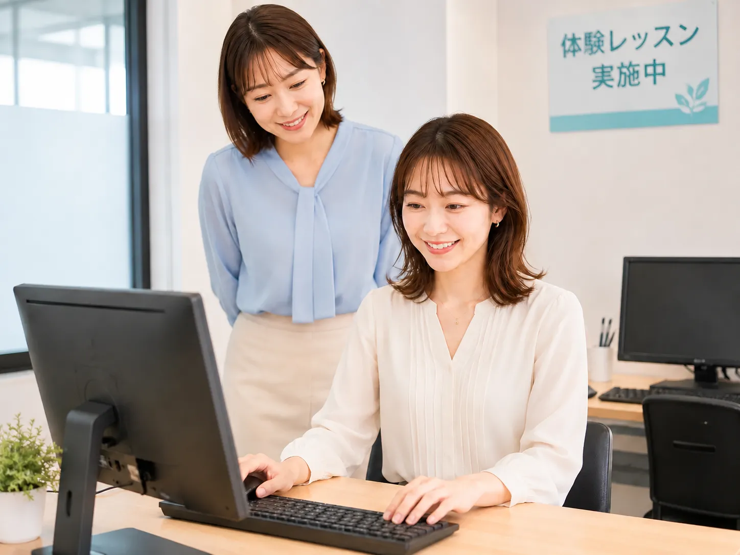 教室で講師のサポートを受けながらパソコンを操作する受講者